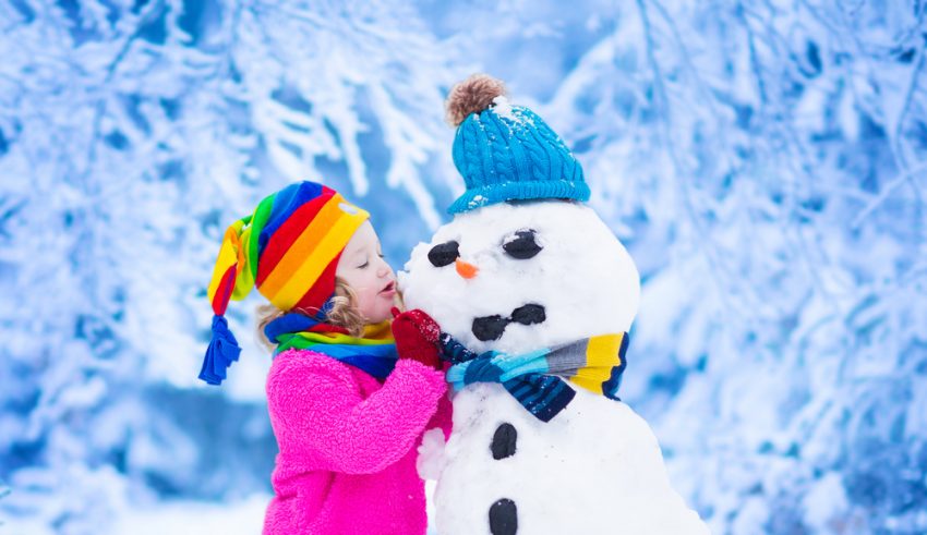Kind im Winter mit Schneemann