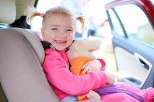 Kleines Mädchen mit Stofftier im Kindersitz