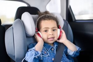 Mädchen mit Kopfhörer im Kindersitz